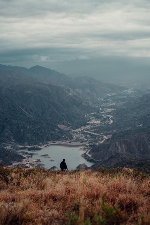 Free Person stands overlooking the dramatic mountainous landscape of La Rioja, Argentina under a cloudy sky. Stock Photo