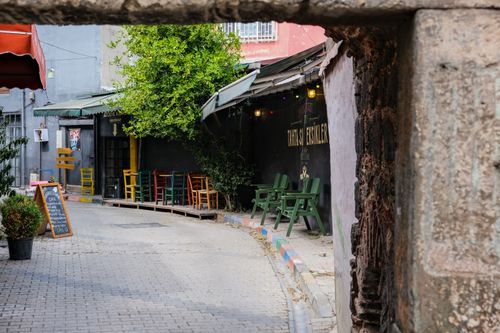 Free Discover a cozy café tucked in a colorful İstanbul alley, adorned with vibrant chairs and rustic charm. Stock Photo