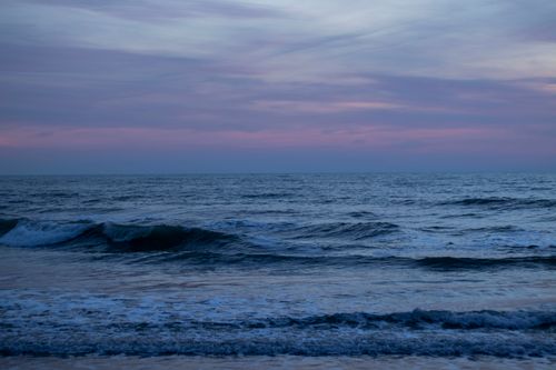Free Peaceful ocean waves under a colorful sky during dusk, offering a tranquil coastal view. Stock Photo