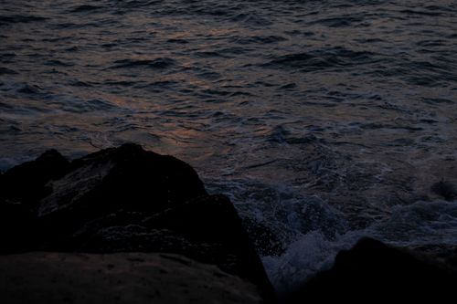 Free Serene view of ocean waves reflecting evening sunset near rocky shore in Mar del Plata, Argentina. Stock Photo