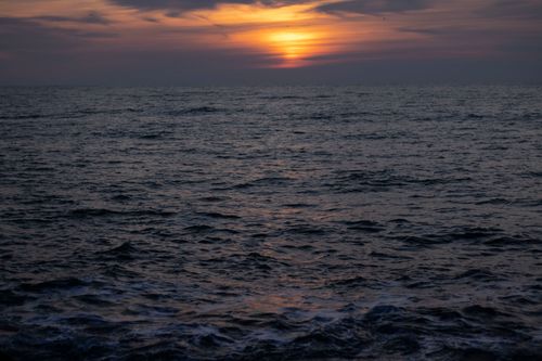 Free Peaceful view of the Atlantic Ocean as the sun sets, creating a warm, harmonious seascape. Stock Photo