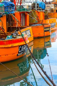 Brightly colored fishing boats docked in Mar del Plata, creating vibrant reflections in the water.
