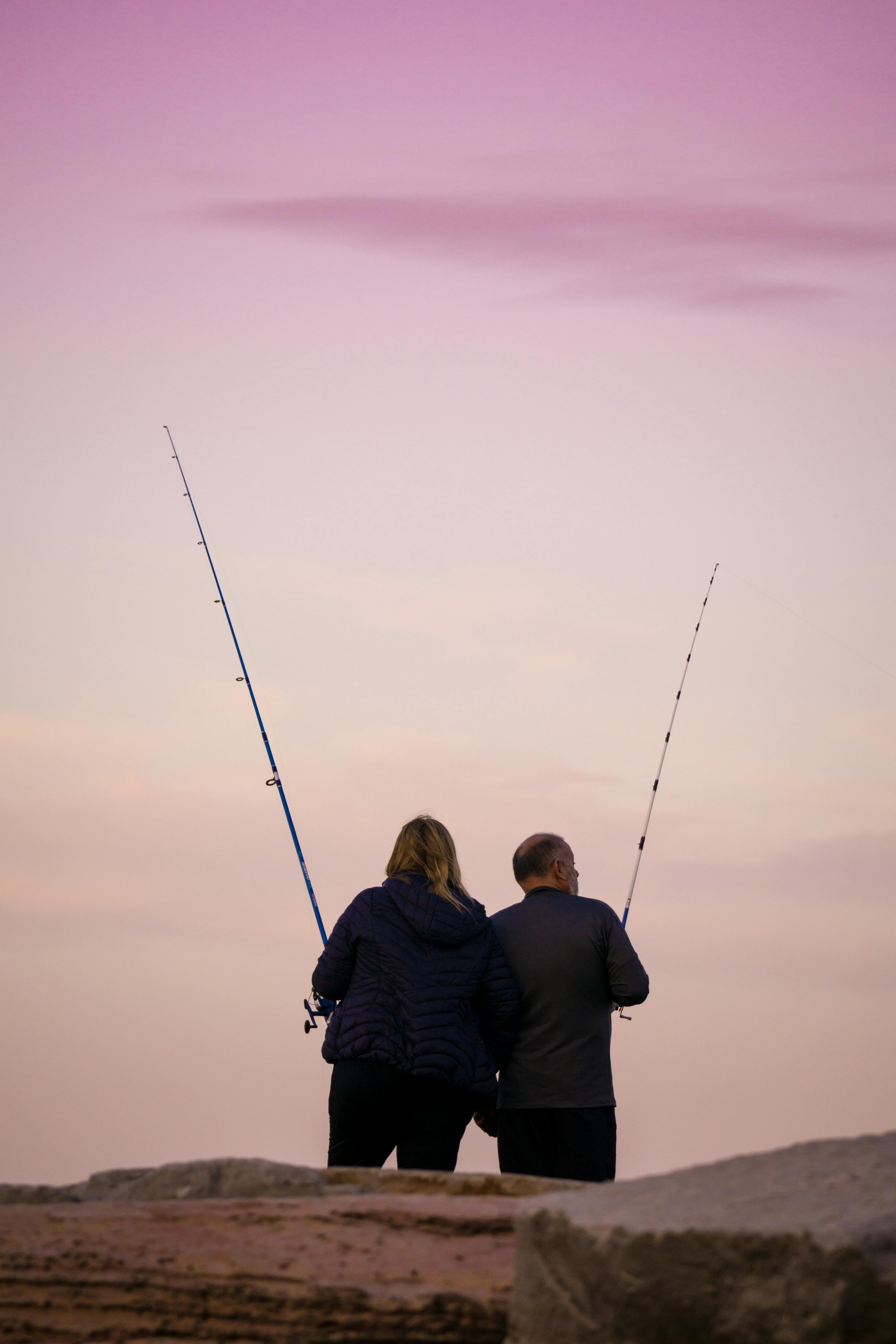 A serene scene of two adults fishing at sunset in Mar del Plata, Argentina.