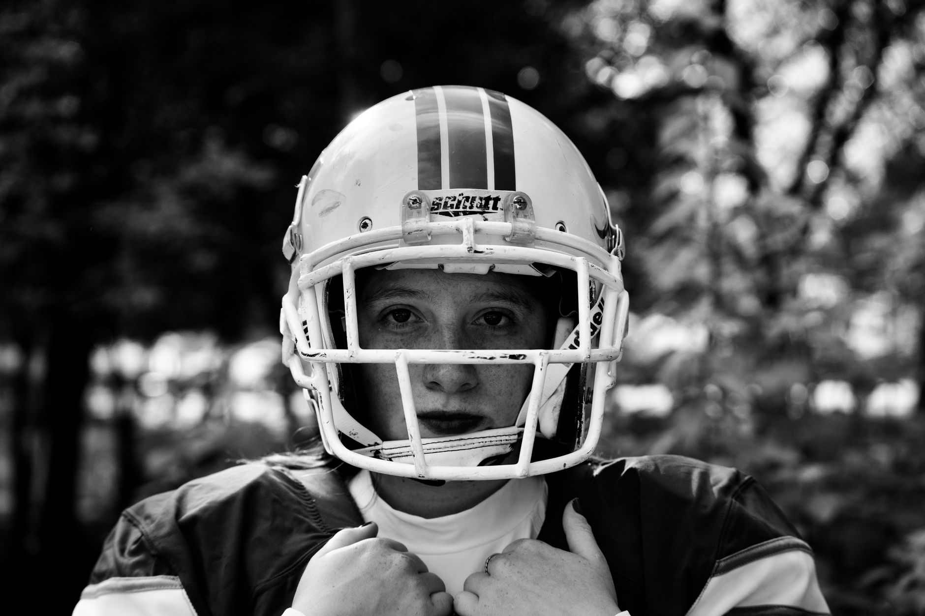 Close-up black and white portrait of a young football player outdoors.