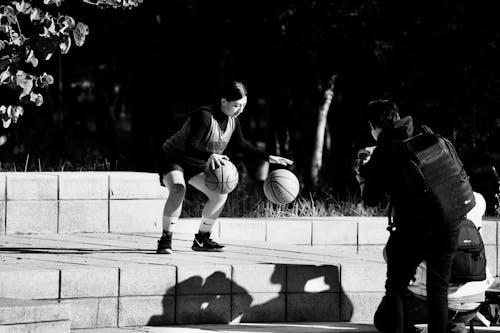 Black and White Photo of Woman Dribbling Balls