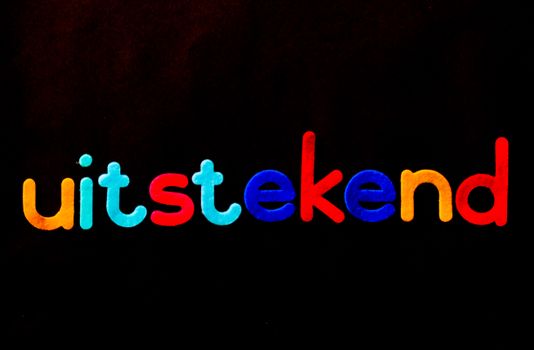 Vibrant 'uitstekend' lettering with colorful design on a black background.