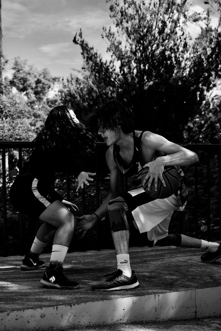 Black And White Photo Of A Young Man And Woman Playing Basketball