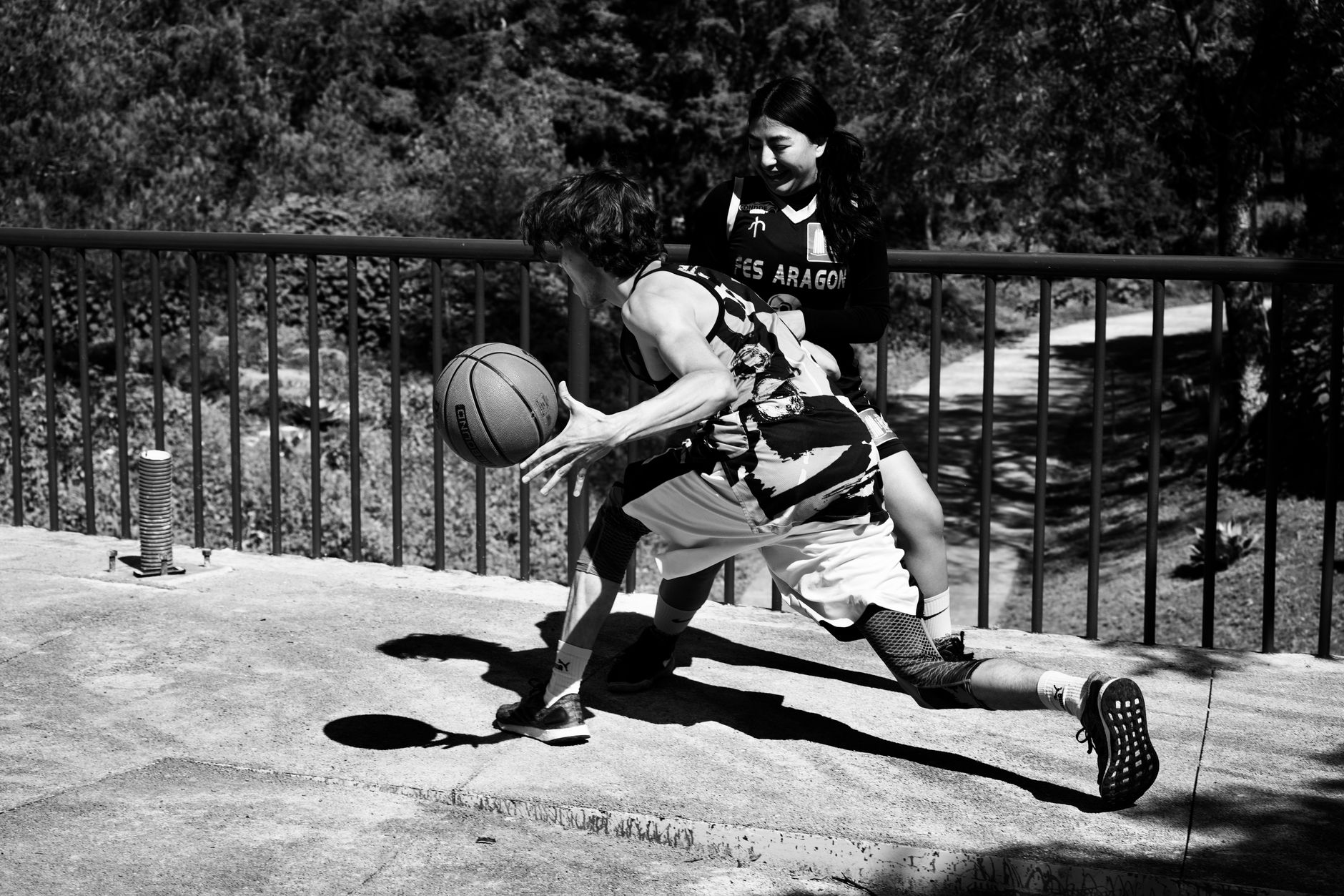 NCAA Basketball photo featuring Two players engaged in an intense basketball match on an outdoor court.