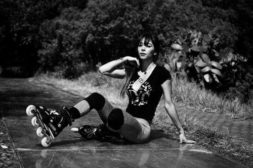 Free A monochrome image capturing a woman sitting on a pathway while wearing rollerblades. Stock Photo