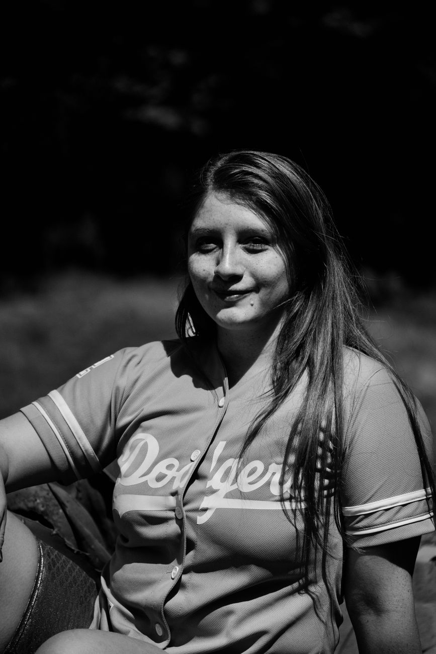 Artistic black and white portrait of a woman wearing a Dodgers jersey outdoors.