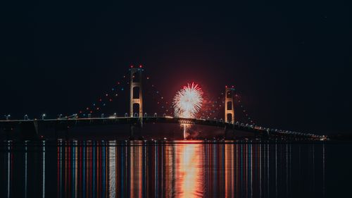 Free Spectacular fireworks display over Mackinac Bridge with reflections on water at night. Stock Photo