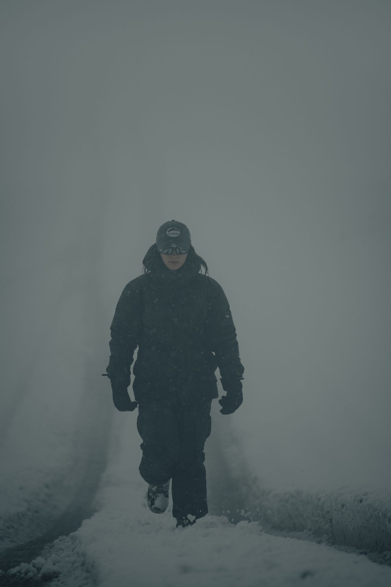 Person walking on a snow-covered foggy road