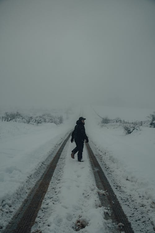 Person Walking on Snow Covered Road