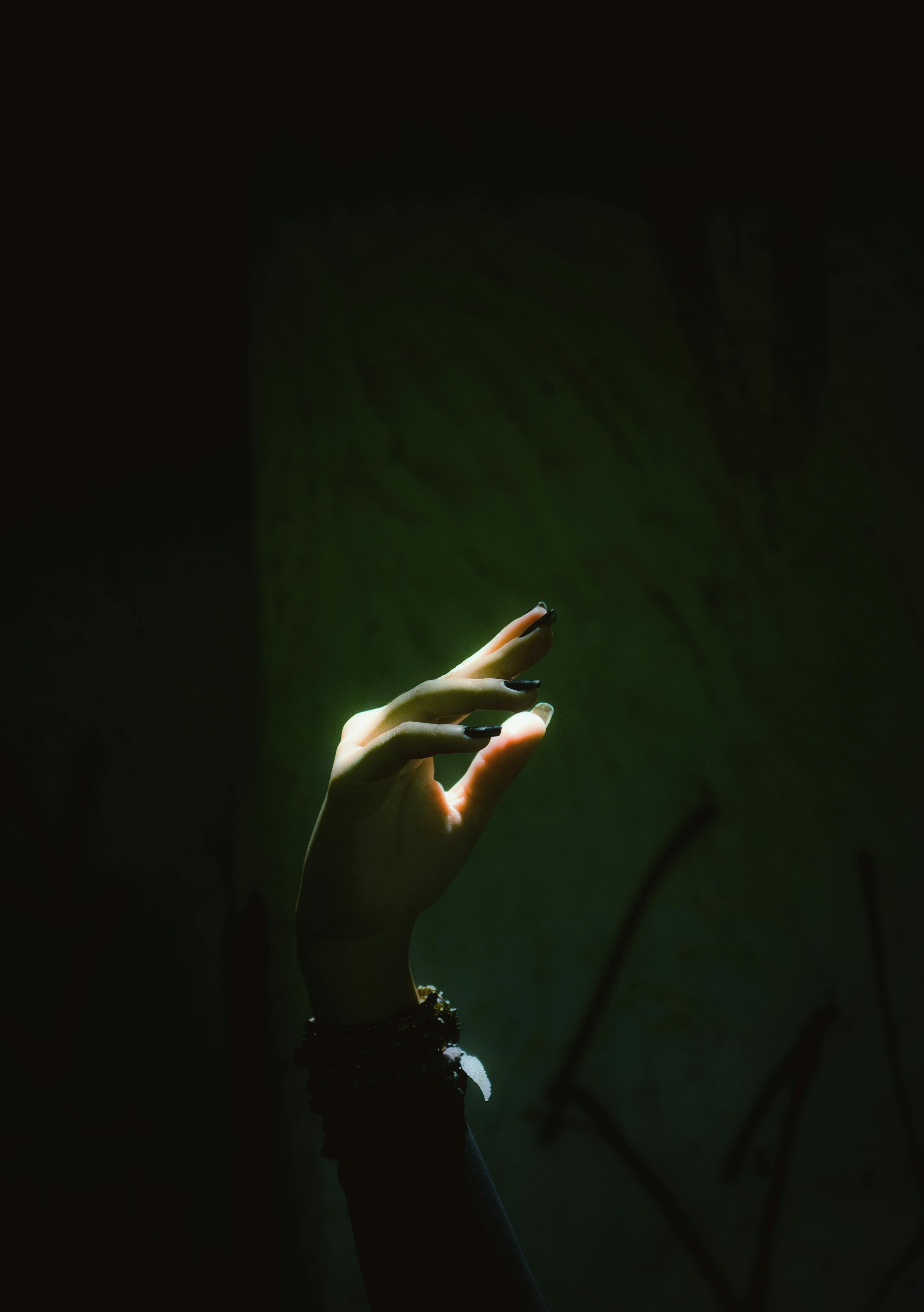 Eerie hand gesture captured in dark lighting, emphasizing contrast and mystery.