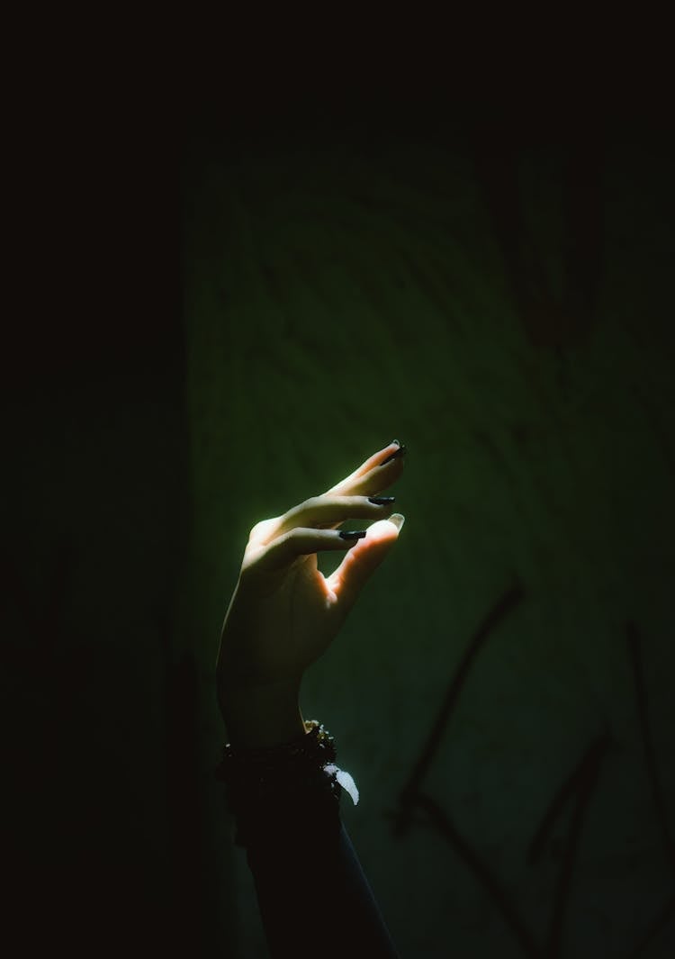 Hand With Long Nails Against Black Background