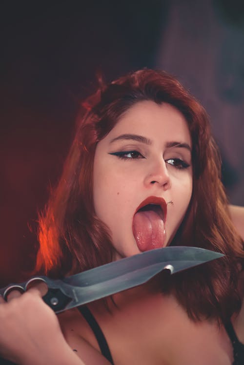 Free A Woman Licking the Sharp Knife she is Holding Stock Photo