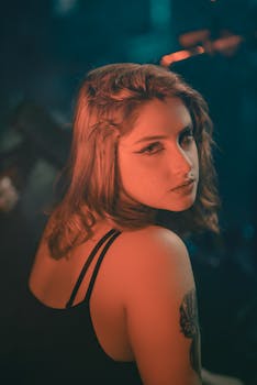 Elegant portrait of a woman with tattoo, captured in moody lighting, showcasing fashion style and expression.