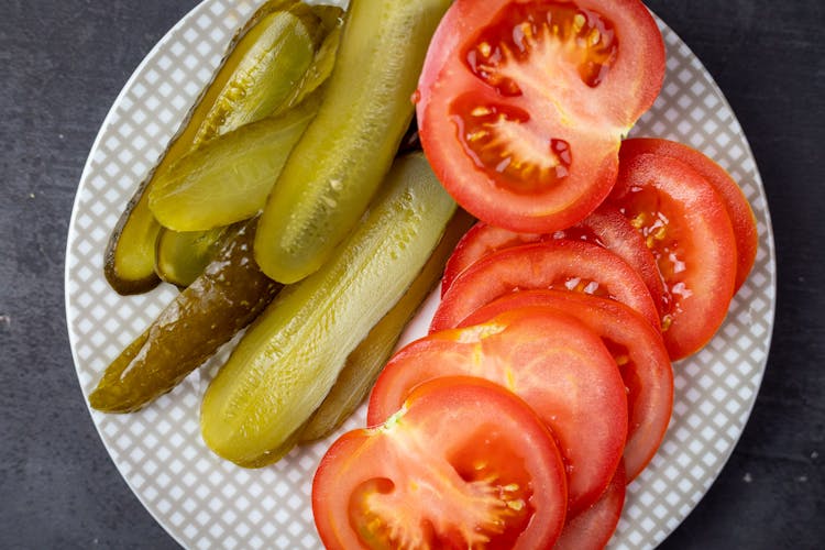 A Close-Up Shot Of Sliced Tomatoes And Pickled Cucumbers