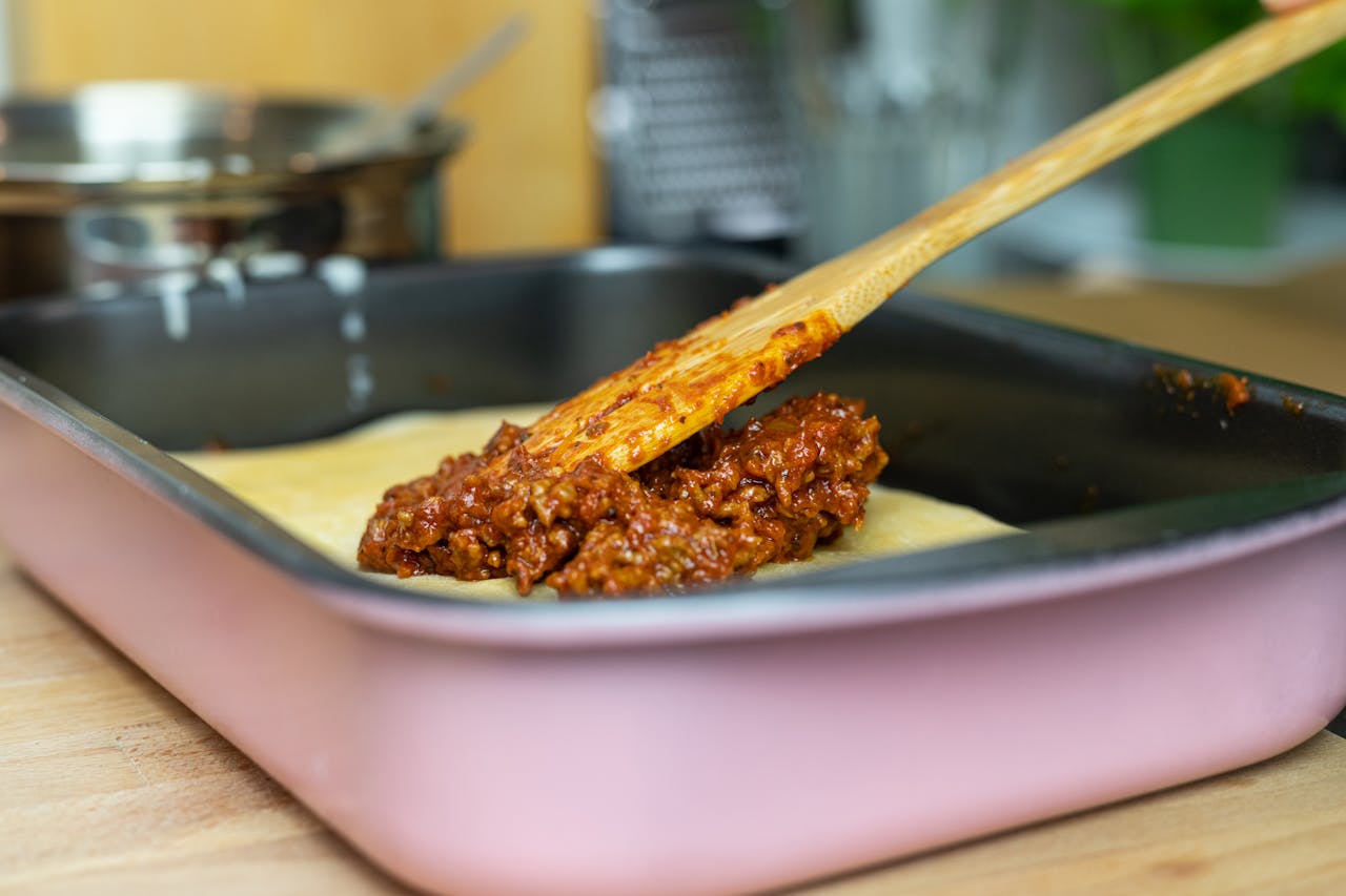 Primo piano mentre si versa ragù e si formano gli strati