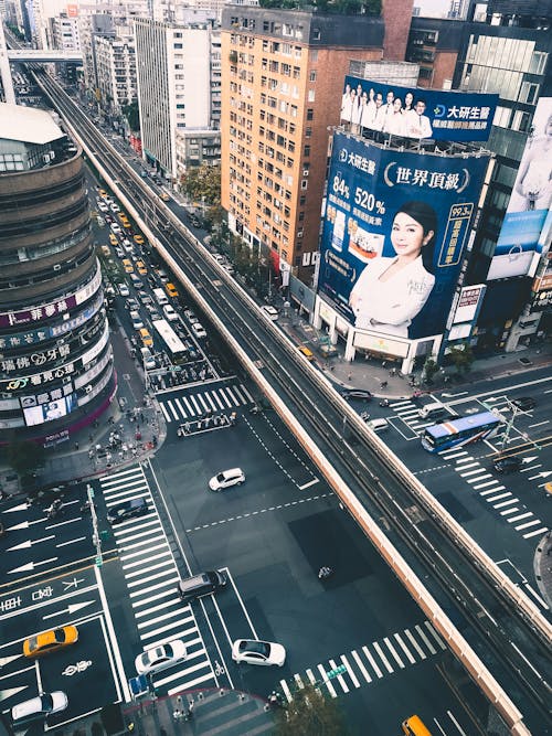 Aerial Photography of Moving Cars on the Road Between City Buildings