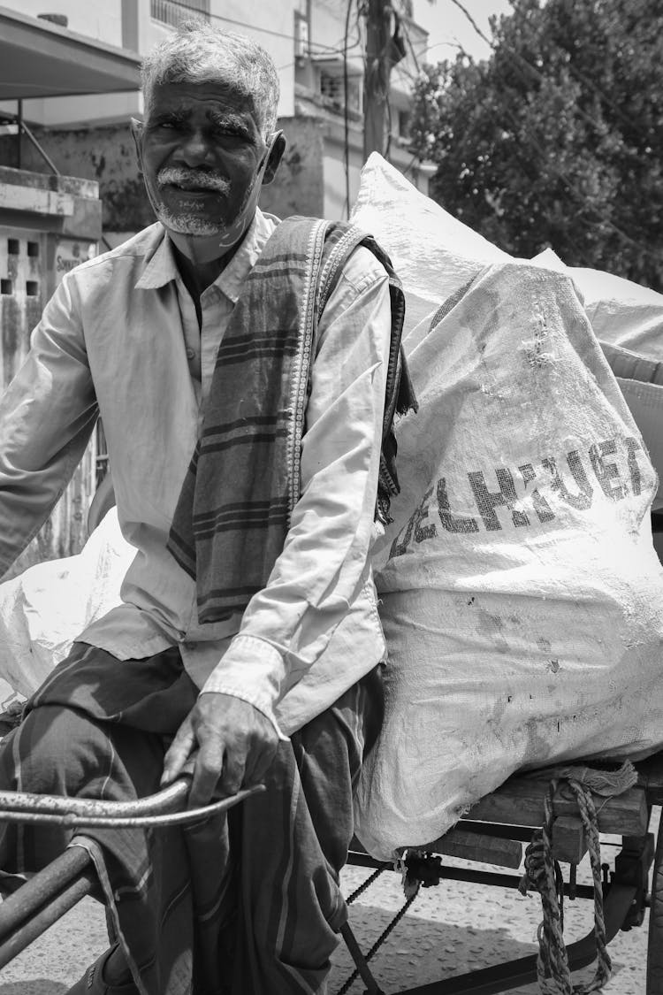 An Elderly Man Driving A Bicycle With Cart