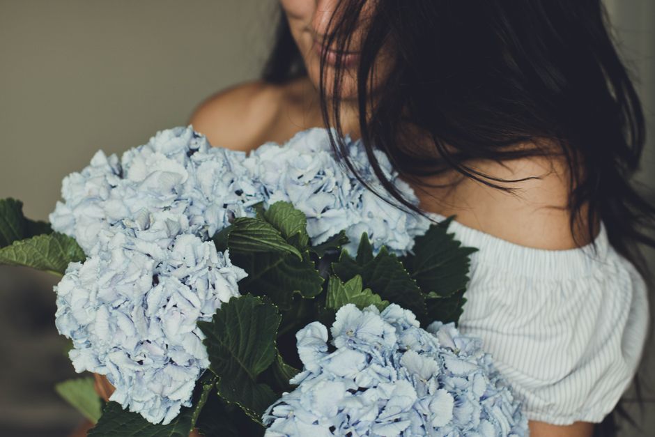 A woman holding a beautiful bouquet of light blue hydrangeas, capturing elegance and romance.