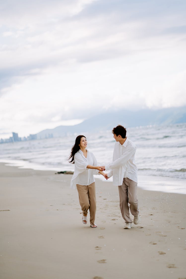 A Couple Running At The Beach