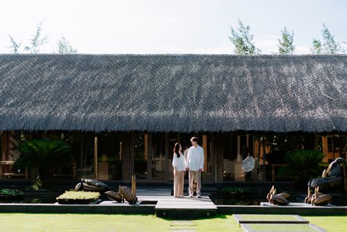 Free Serene couple by a tropical bungalow, ideal for vacation and relaxation imagery. Stock Photo