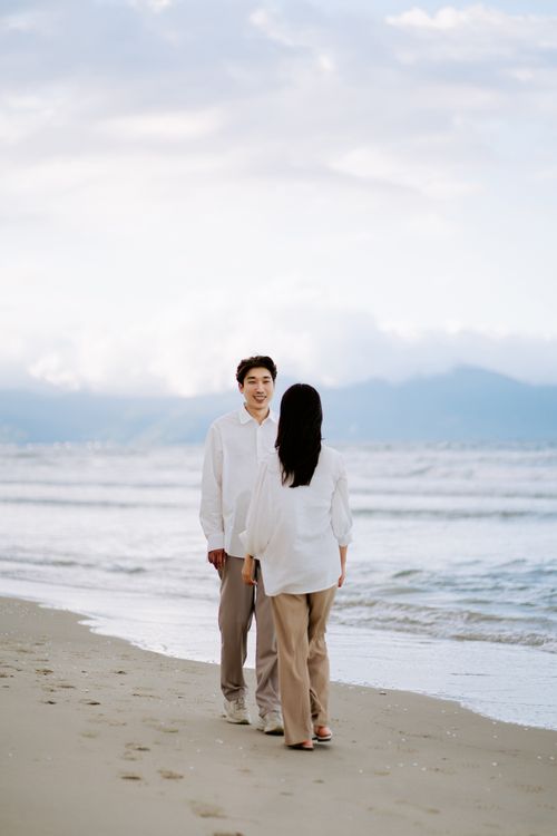 Free Couple walking on the beach, smiling and enjoying a serene moment by the ocean. Stock Photo
