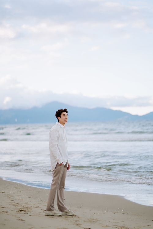 Free A man standing on a beach enjoying a peaceful sea view. Stock Photo
