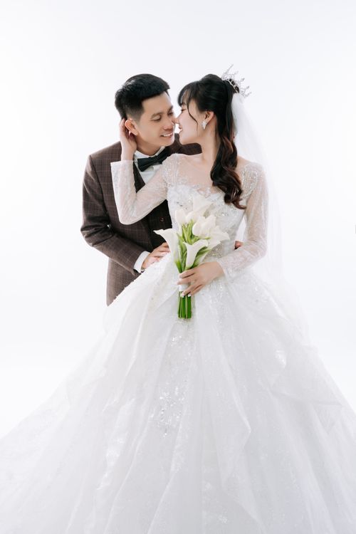 Free Asian couple in wedding attire embracing with joy against a white background. Stock Photo