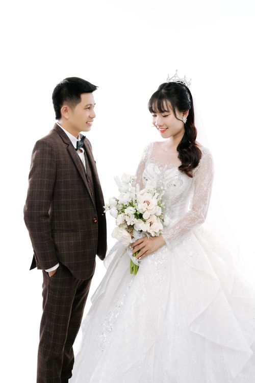 Free Charming portrait of an Asian couple in wedding attire with a white floral bouquet. Stock Photo