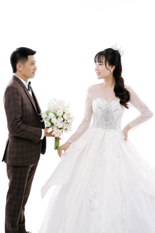 Free Asian bride and groom posing in studio, smiling in elegant wedding attire. Stock Photo