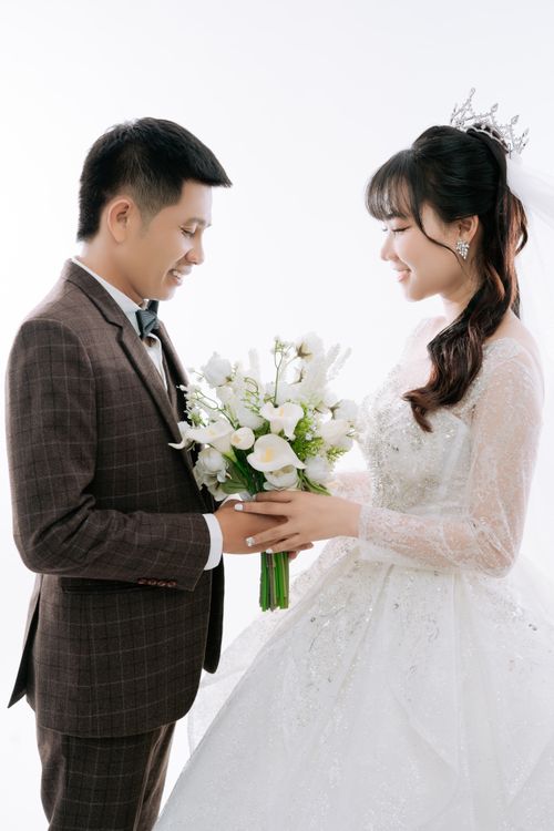Free A bride and groom share a joyful moment holding a bouquet, symbolizing love and happiness. Stock Photo