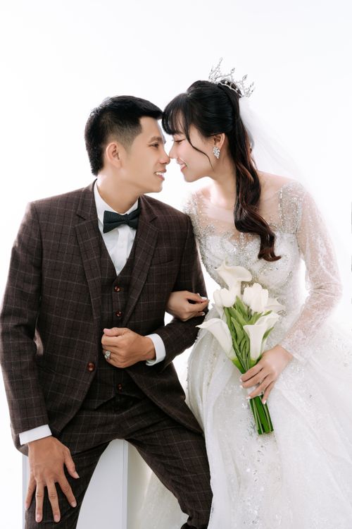 Free Beautiful Asian couple in wedding attire, smiling and posing together with a flower bouquet. Stock Photo
