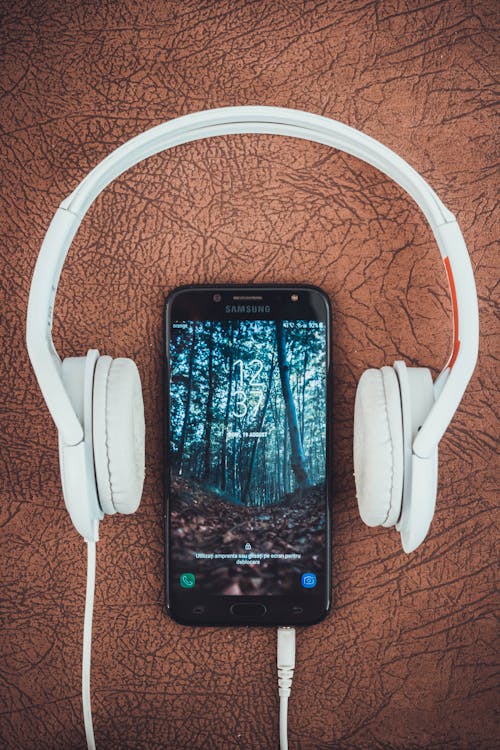 Eingeschaltetes Schwarzes Samsung Smartphone Zwischen Kopfhörern