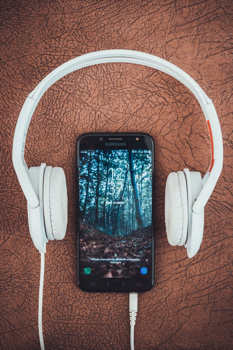 Turned-on Black Samsung Smartphone Between Headphones