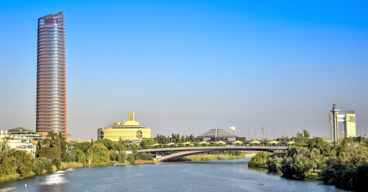 View of a modern skyscraper and bridge over the Guadalquivir River in Seville, Spain.