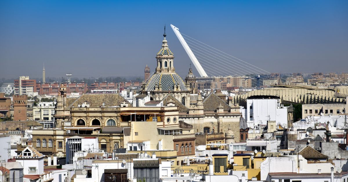 Vista aérea del skyline de Sevilla con el Puente del Alamillo y la arquitectura histórica de la ciudad bajo un cielo azul despejado