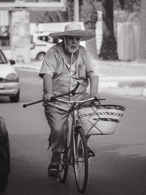 A Man Wearing a Hat Riding a Bicycle 
