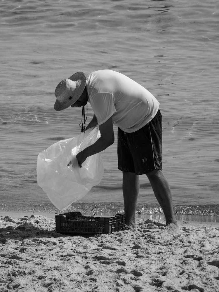 Man Collecting Things On A Beach In Black And White 