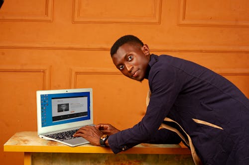 African Man Working on Laptop in Orange Room 