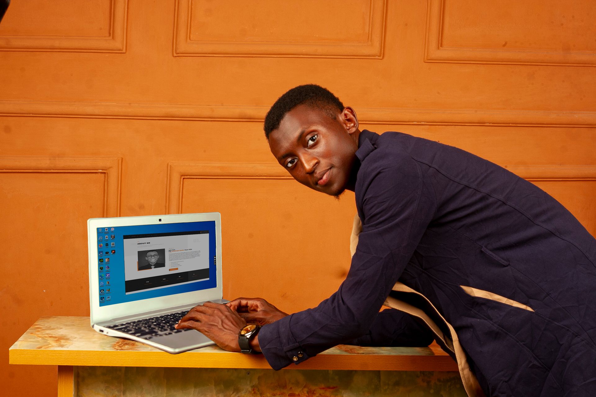 African man in a stylish office setting using a laptop, emphasizing modern business technology.
