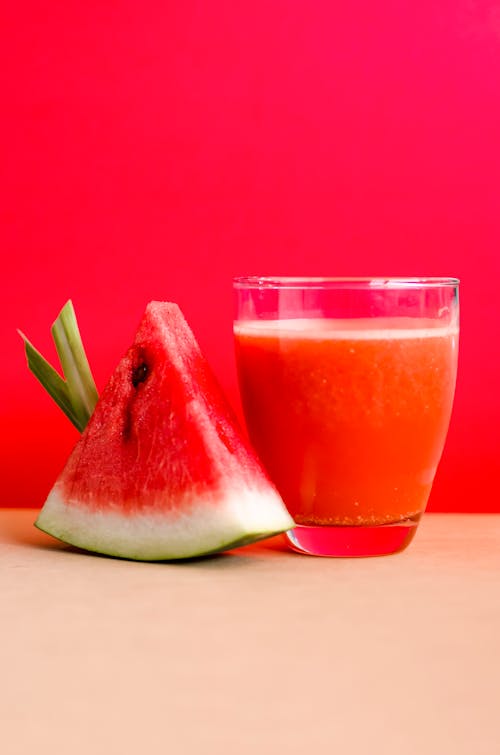 Free Mit Wassermelonenshake Gefüllte Glasschale Neben Geschnittenen Wassermelonenfrüchten Auf Brauner Oberfläche Stock Photo