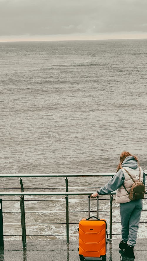 Woman in Blue Jacket Sitting on Green Metal Railings