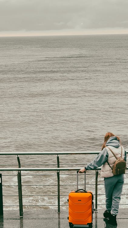 Woman in Blue Jacket Sitting on Green Metal Railings