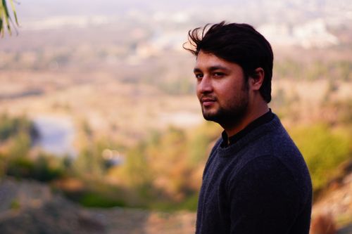 Free A young man with a beard posing outdoors with a scenic nature backdrop. Stock Photo