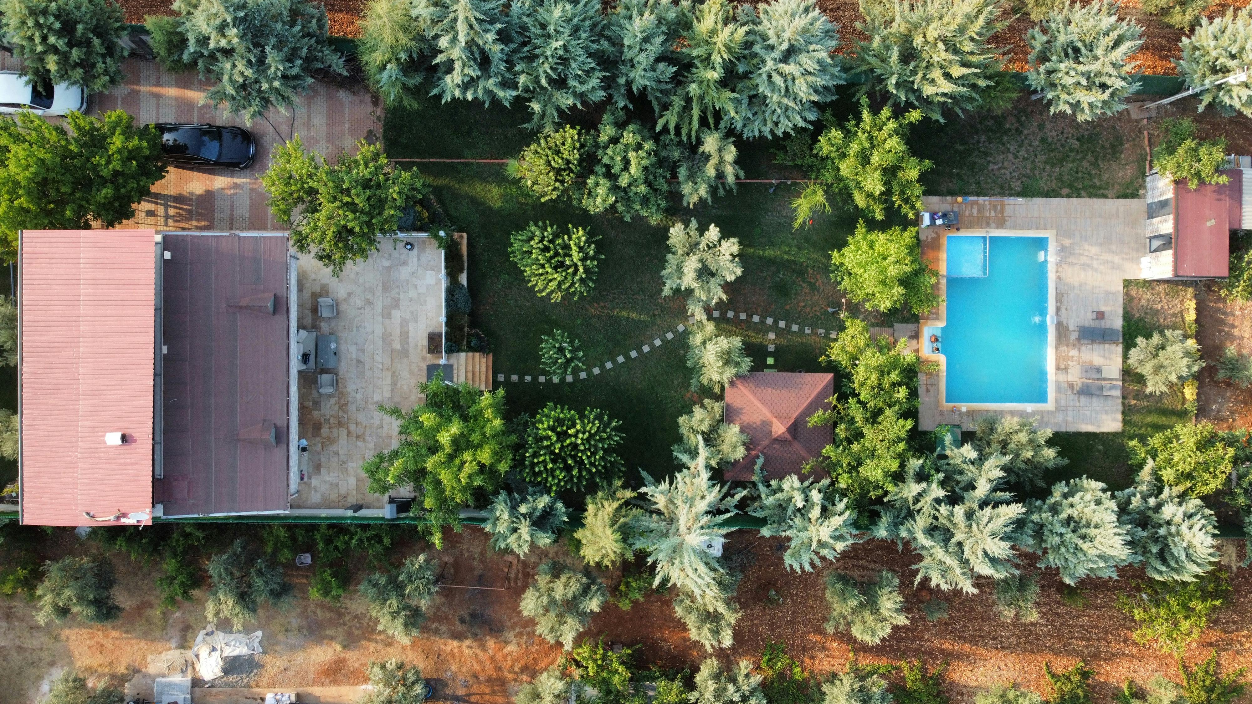 Top-down aerial shot of a villa with a swimming pool amidst trees, showcasing elegant outdoor living. - Photo by izzet çakallı on Pexels