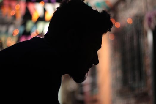 Artistic silhouette of a man with vibrant festive lights in the background, creating a dramatic effect.