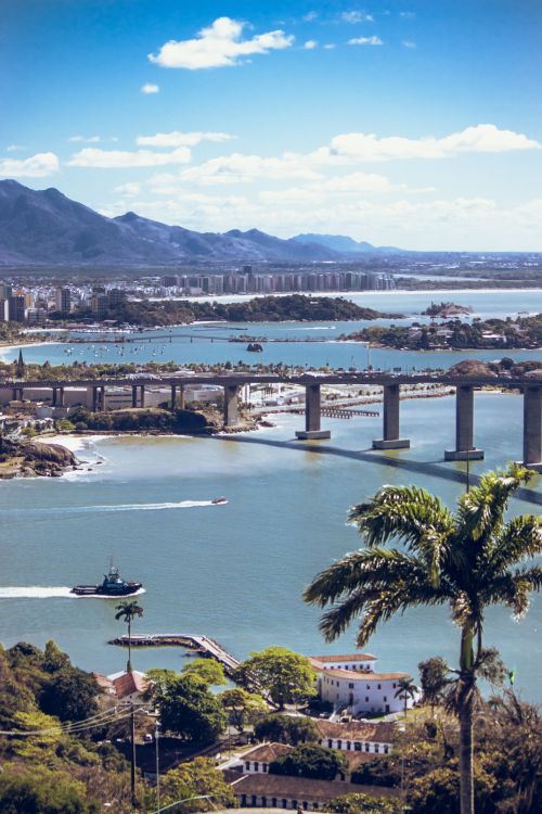 Free Scenic aerial view of Vitória, Brazil featuring a bridge, lush greenery, and ocean landscape. Stock Photo